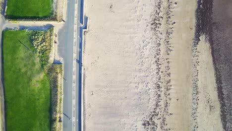 Birds-Eye-Aerial-View-Of-Sandy-Beach-Front-And-Green-Grass-On-A-Bright-Sunny-Day