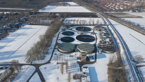 wide-aerial-of-sewage-water-treatment-plant-in-winter---drone-flying-backwards