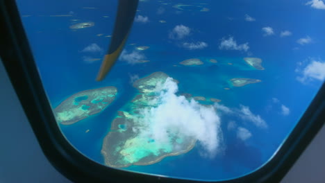 View-out-window-of-prop-plane-flying-over-small-Pacific-islands