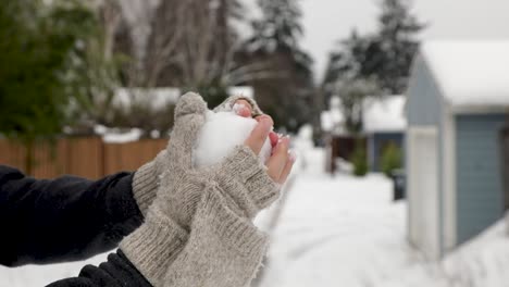 Close-up-of-person-with-gloves-forming-a-snowball-and-throwing-away-during-cold-winter-day-in-residential-area