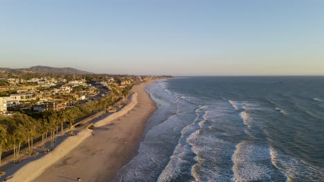 Scenic-aerial-view-of-Pacific-ocean-waves-breaking-into-California-shoreline