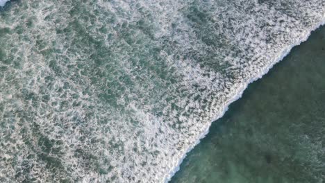 4K-aerial-top-view-of-waves-foam-in-beautiful-turquoise-sea-texture-background