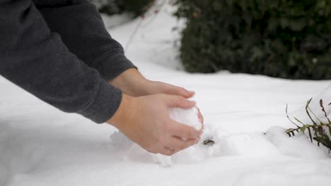 Caucasian-hands-forming-round-snowball-of-deep-snow-after-snowstorm-in-winter