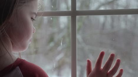 Child-watching-the-snow-falling-outside-the-window