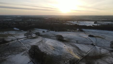 Sunrise-over-snow-covered-fields-winter-UK-low-sun-aerial-4k
