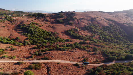 Van-on-dirt-road-in-the-red-mountains-of-Tarifa,-Andalusia