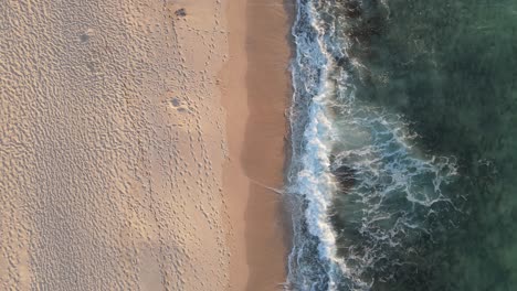 4K-fly-out-of-waves-and-sand-coast-in-beautiful-turquoise-sea-texture-background-top-view-aerial