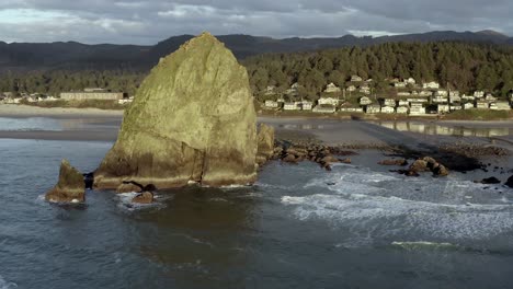 Haystack-Rock-at-Cannon-Beach-in-Oregon,-sunset-over-ocean,-aerial-view
