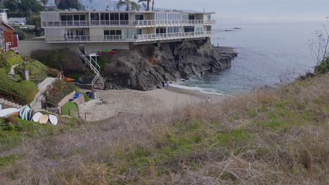 Rising-through-the-grass-to-reveal-a-small-beach-next-to-a-cliff-side-apartment,-in-Laguna-Beach,-California