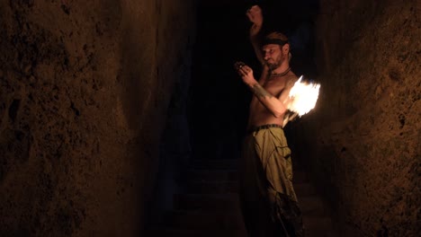 Cinematic-shot-of-a-fire-performer-juggling-fire-balls-in-a-dark-cave