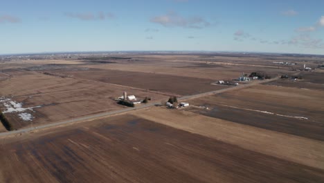 Barn-and-silo-of-farm-surrounded-by-brown-fields-in-late-winter