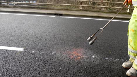 Contractor-with-propane-gas-flame-torch-melting-tarmac-road-asphalt-marking-paint