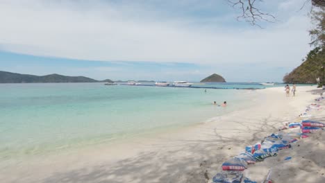 Soft-sandy-beach-bathed-by-emerald-crystal-clear-water-in-Koh-Hey-,-Thailand---Wide-slide-Reveal-Shot
