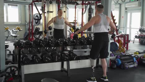 Man-with-prosthetic-leg-lifting-dumbbells-during-gym-workout