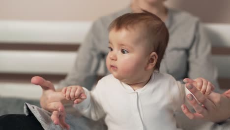 Little-beautiful-baby-girl-holding-her-mother's-fingers-trying-to-sit-down