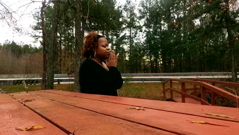 Black-woman-in-her-40's-sitting-in-park-on-a-rainy-day-praying-in-North-Carolina
