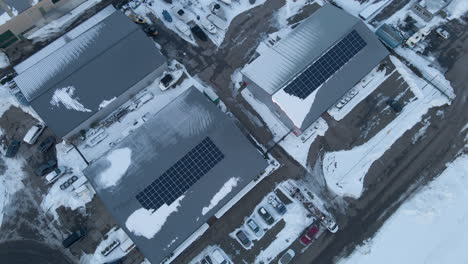 Aerial-of-solar-panels-on-industrial-warehouses-in-winter---drone-lifting-up-and-tilting-down