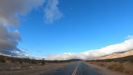 Driving-down-an-empty-stretch-of-road-in-the-middle-of-the-Mojave-desert-wilderness---point-of-view