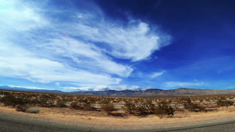 Watching-the-scenery-along-a-desert-highway-on-a-picturesque-day-with-mountains-in-the-distance---passenger-point-of-view