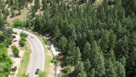 Cars-driving-down-a-canyon-road-along-side-a-stream