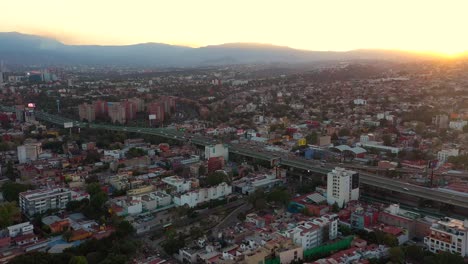 Aerial-drone-view-of-dramatic-sunset-over-a-highway-and-the-cityscape,-in-Mexico-city,---lateral,-tracking,-dramatic-shot