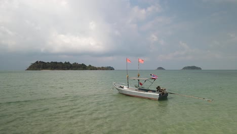 Bote-Pequeño-Con-Bandera-Tailandesa-En-El-Océano-Tropical-Con-Islas-Detrás-En-Clima-Ventoso