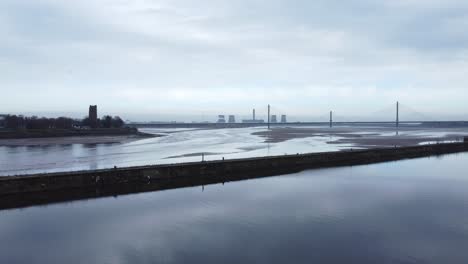 Aerial-across-River-Mersey-Runcorn-low-tide-canal-entrance-old-town-waterfront-push-in-slow