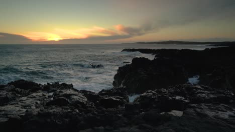 Ocean-Waves-Crashing-On-Rocky-Shore-At-Sunset---wide-shot