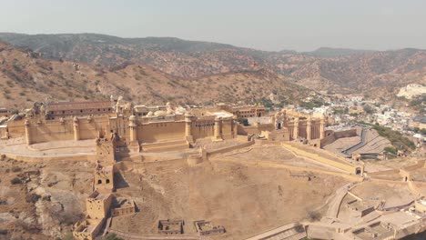 Glorreiche-Bernsteinfarbene-Festung,-Die-Auf-Einem-Terrassierten-Plateau-Eines-Kargen-Berges-In-Jaipur,-Rajasthan,-Indien-Steht---Panoramaaufnahme-Aus-Der-Luft-Mit-Weitem-Orbit