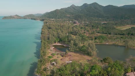 Drohnenblick-über-Die-Palmen-Am-Leeren-Küstenstrand-Mit-Bergen-Auf-Der-Tropischen-Insel