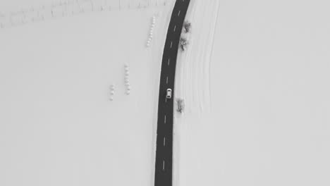 Aerial-Tracking-Shot-Of-A-Car-Driving-On-Adventure-In-Snow-Covered-Winter-Scene