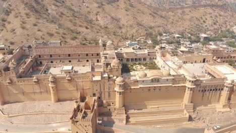 Weiter-Blick-Auf-Das-Bernsteinfarbene-Fort-Jaleb-Chowk-Und-Aram-Bagh,-Umgeben-Von-Kargen-Hügeln-In-Jaipur,-Rajasthan,-Indien---Weiträumige-Panoramische-Umlaufbahnaufnahme-Aus-Der-Luft