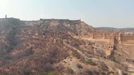Weites-Panorama-über-Die-Kargen-Hügel,-Die-Das-Bernsteinfort-In-Jaipur,-Rajasthan,-Indien-Umgeben---Luftpanorama-Umlaufbahnaufnahme