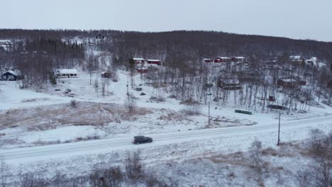 Car-travelling-through-desolate-winter-frozen-landscape---Low-angle-aerial-side-tracking-shot