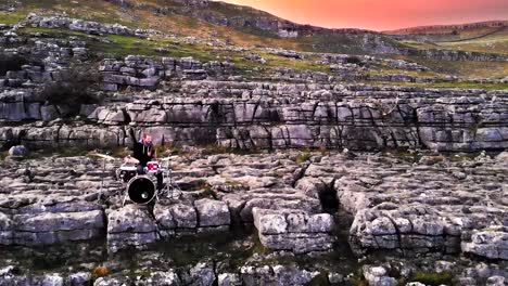 Drummer-playing-solo-on-the-cliff-rocks-at-sunset,-Malham-Cove-England