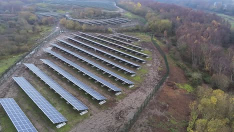 Solar-panel-array-rows-aerial-view-misty-autumn-woodland-countryside-left-orbit-low