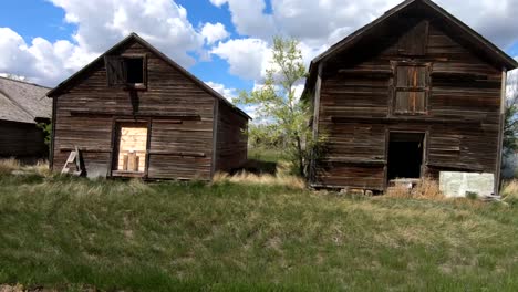 A-old-abandoned-barns-on-farm-land-during-a-nice-day-with-clouds-in-the-sky