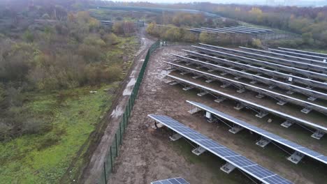 Solar-panel-array-rows-aerial-view-misty-autumn-woodland-countryside-pull-back-low
