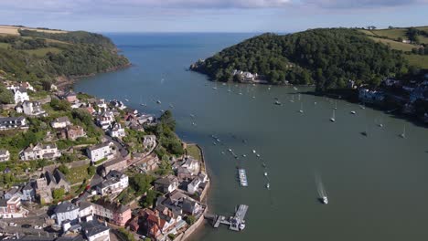 Aerial-cinematic-view-over-Dart-river-in-Kingswear,-Devon-w-UK,-many-sailing-boats-and-historical-building-on-left-shore