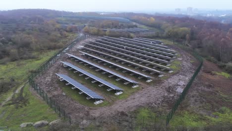 Solar-panel-array-rows-aerial-view-misty-autumn-woodland-countryside-fast-left-orbit