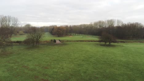 Aerial-view-overcast-frosty-green-golf-course-country-club-fairway-forward-rising