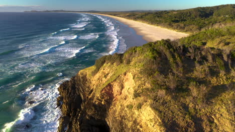 Cinematic-drone-shot-of-Broken-Head-coast-near-Byron-Bay,-starting-on-rocky-outcropping-then-moving-to-sandy-beach