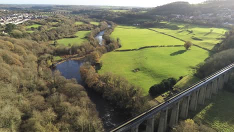 Old-Welsh-Pontcysyllte-Aqueduct-waterway-aerial-view-rural-Autumn-woodlands-valley-high-left-orbit-above-countryside