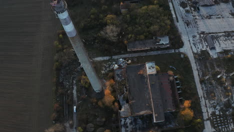 Wide-aerial-shot-of-abandoned-old-industrial-factory-with-chimney-at-sunset