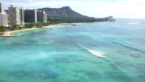 Aerial-view-over-Waikiki-Beach-with-many-surfers-in-Honolulu,-Hawaii