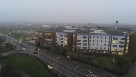 Aerial-view-British-NHS-hospital-on-misty-wet-damp-morning-slow-rising-shot