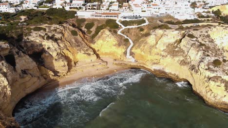 Waves-crashing-into-sandstone-cliffs-in-Carvoeiro,-Algarve,-Portugal