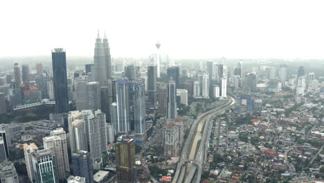 Aerial-view-of-Kuala-Lumpur-highway-and-city-skyline,-tilt-up-reveal