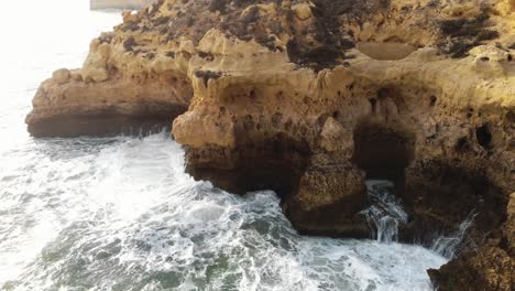 Aerial-4K-drone-footage-revealing-the-rocky-coastline-cliffs-near-city-of-Carvoeiro,-Portugal