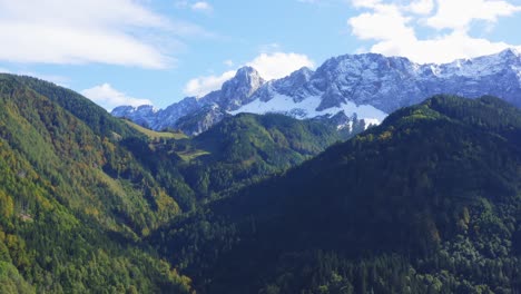 Luftaufnahme-Der-Bewaldeten-Hügellandschaft-Mit-Schneebedeckten-Bergen-Im-Hintergrund